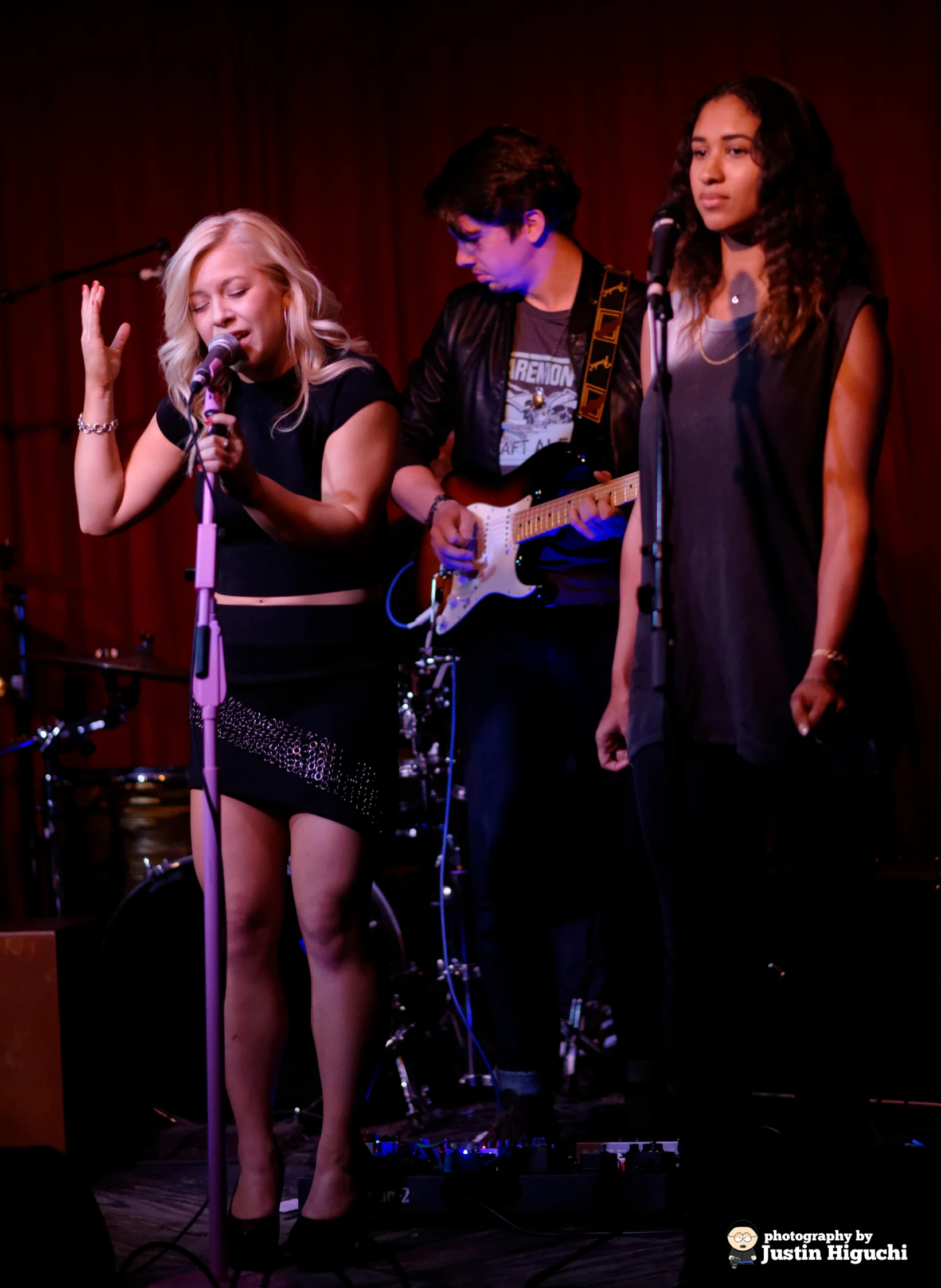 a group of women and a boy standing in front of a microphone on stage