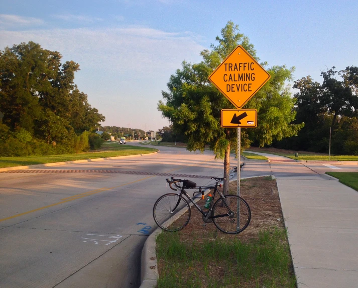 a bike parked underneath a street warning sign