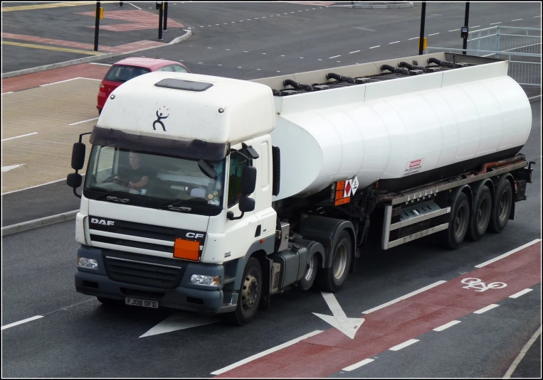 a large truck with tanker is driving down the road
