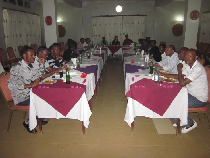 several people are sitting at table eating together