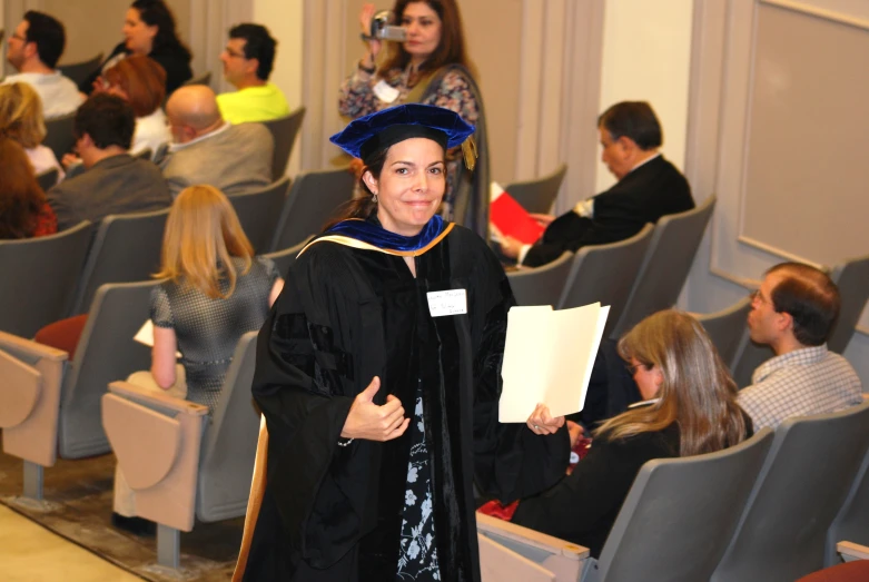 a woman in a cap and gown holding a certificate