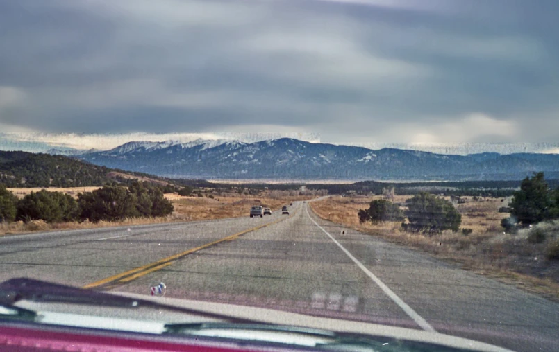 cars going down the road and hills seen from a car window