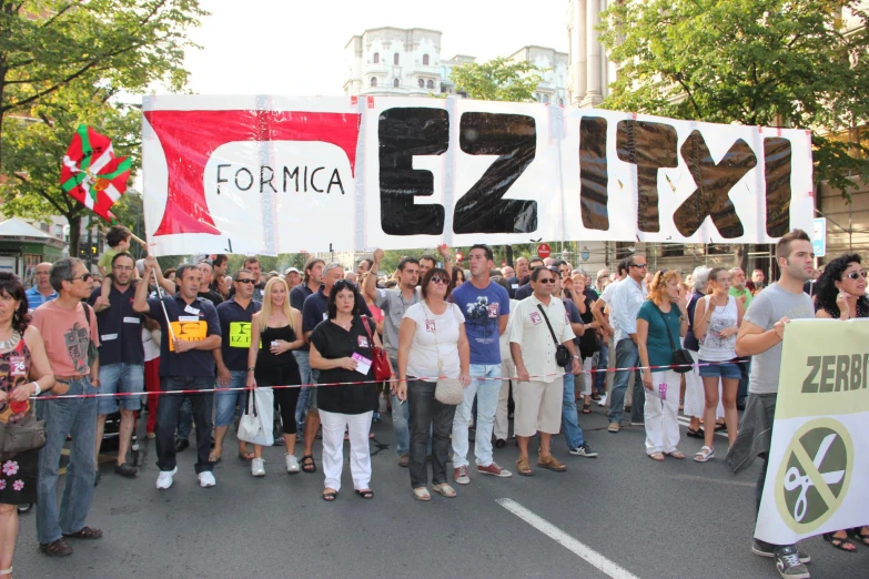 a group of people standing next to each other holding a large sign