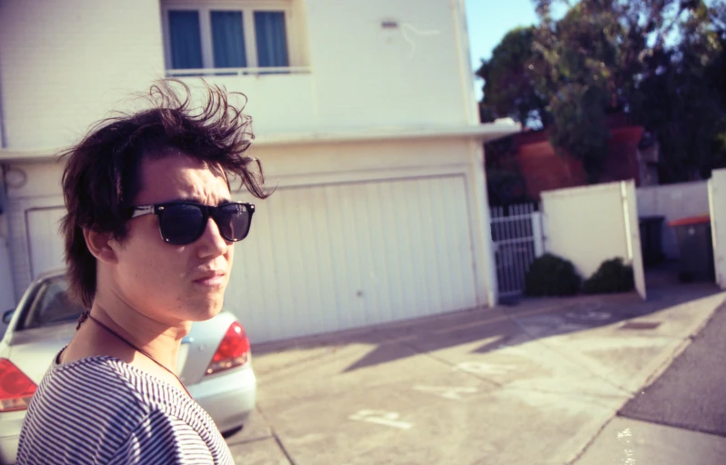 young man in sunglasses near a parked car