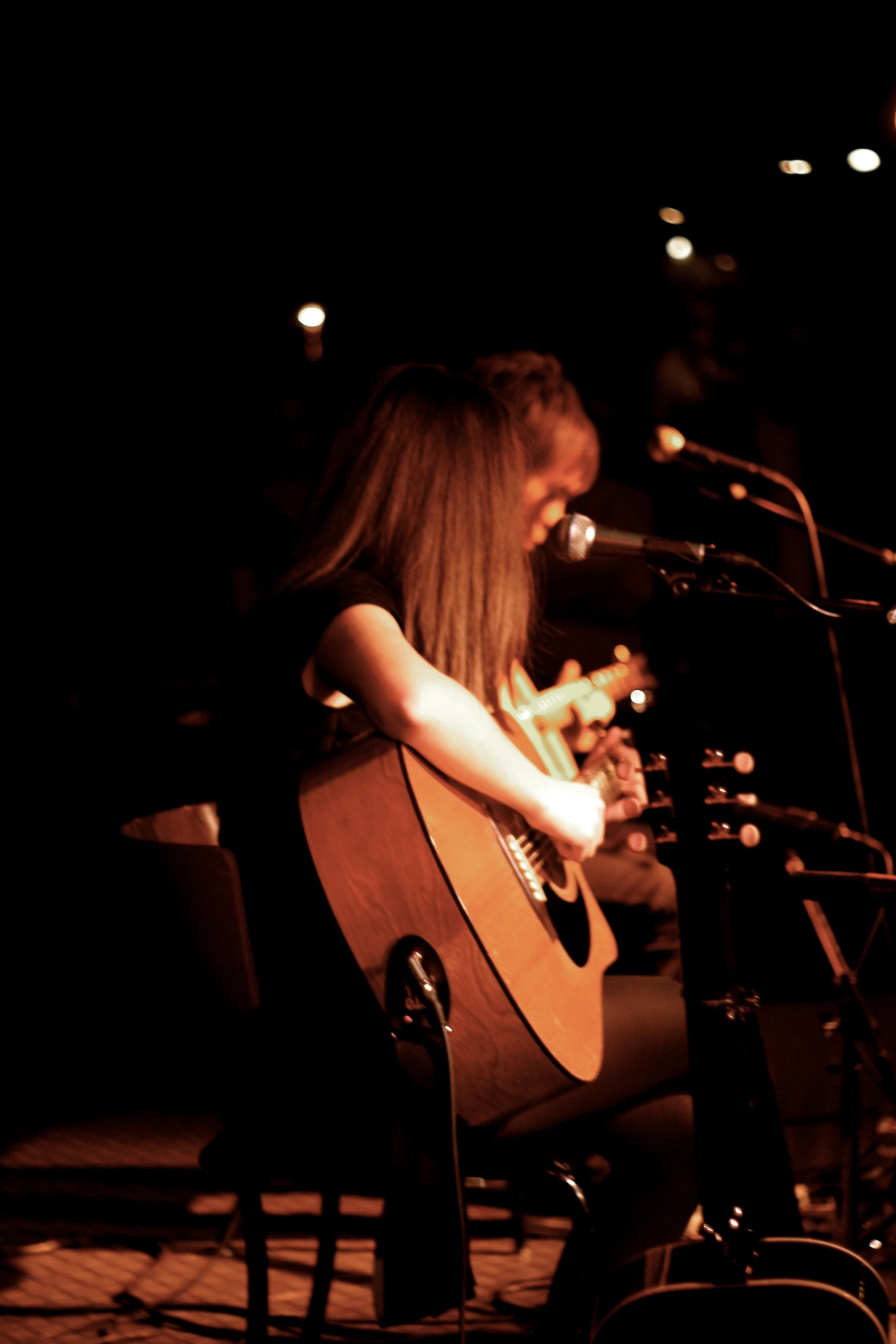 a woman sitting in front of a microphone with an acoustic guitar