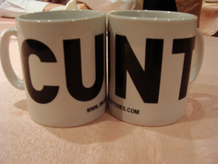 two mugs are sitting on a table with the letters