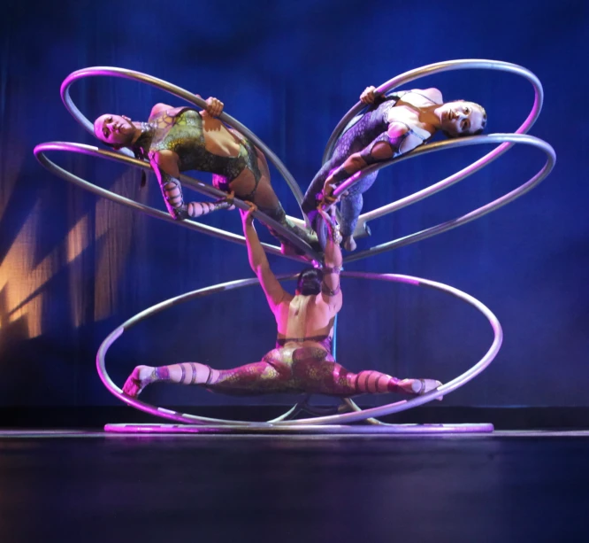 two female dancers performing on a round metal pole