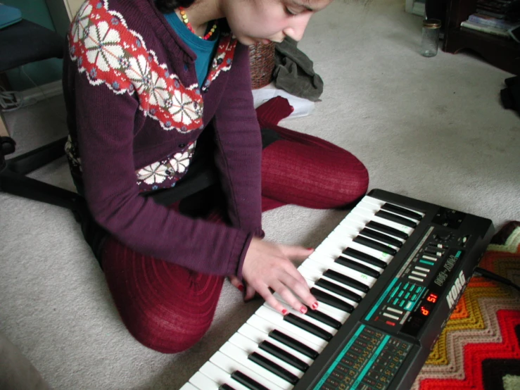 a person sitting down playing an electronic keyboard