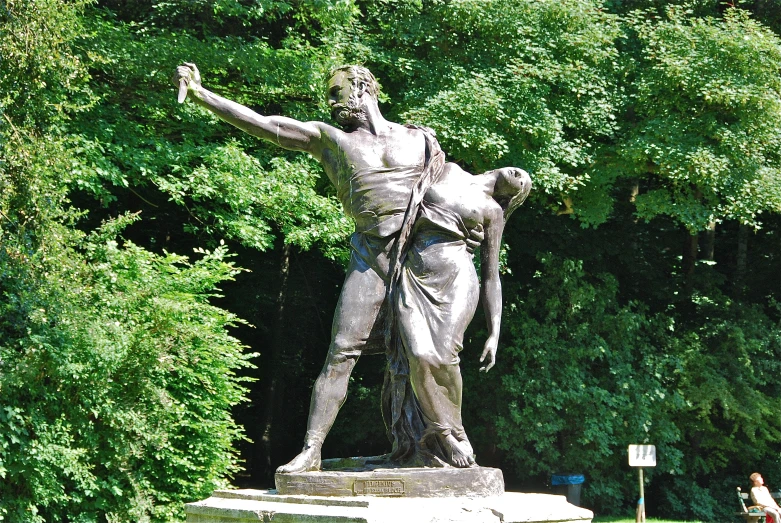 a woman walking past a statue of a man in a park