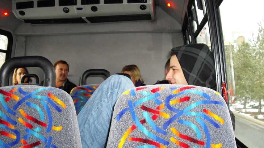 people sitting on and standing next to each other on a bus