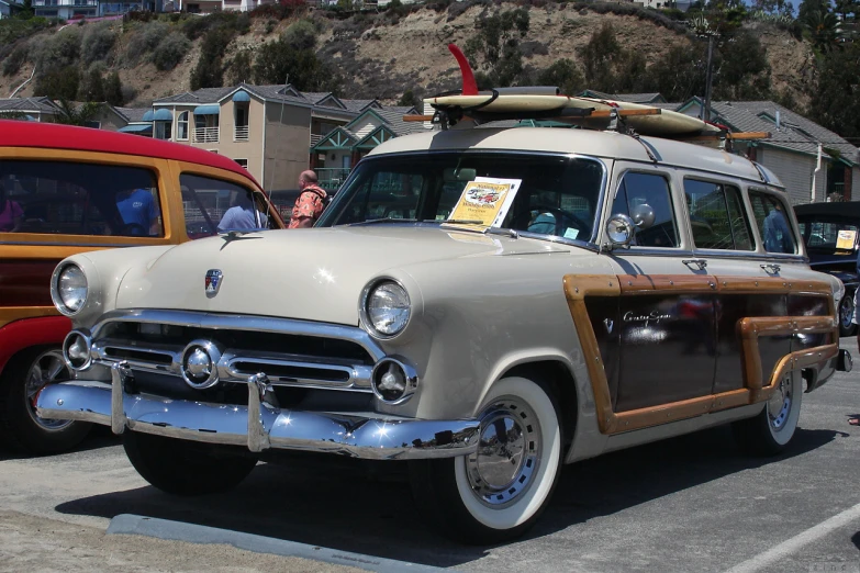 a gray and brown classic car parked next to some red vans