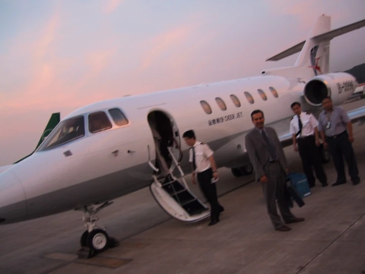 a plane on the ground with several passengers boarding it