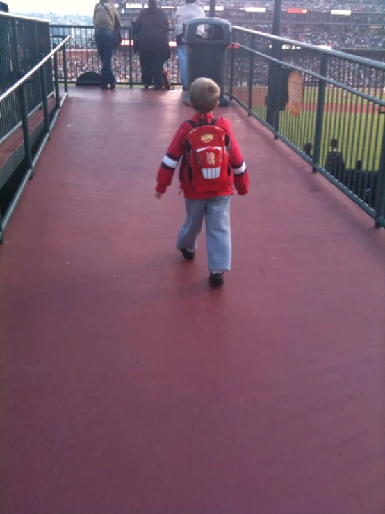 small child in red jacket walking up to the bleachers