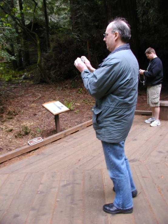 the man in the coat is standing on a boardwalk