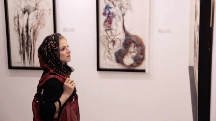 woman in head scarf standing in front of art work