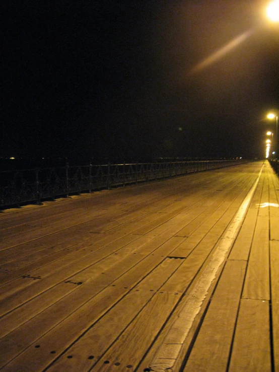 a empty bridge at night with light shining from the lanterns