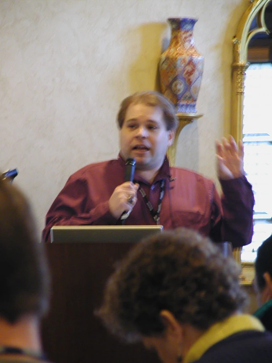 a man speaking on a stage in front of a crowd