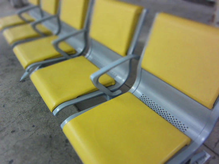 a row of yellow and silver benches on the pavement