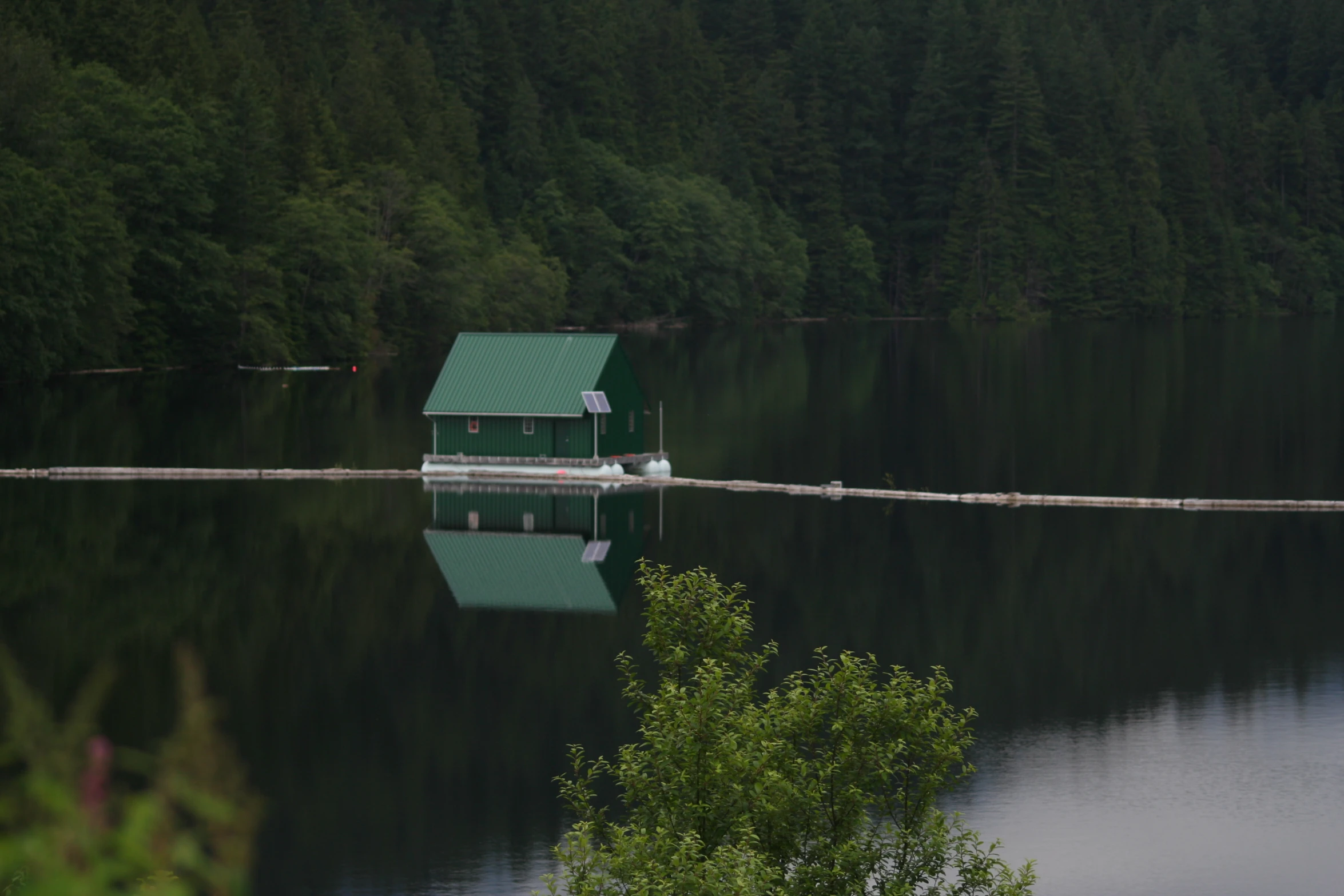 a small house on top of a lake in the middle of some woods