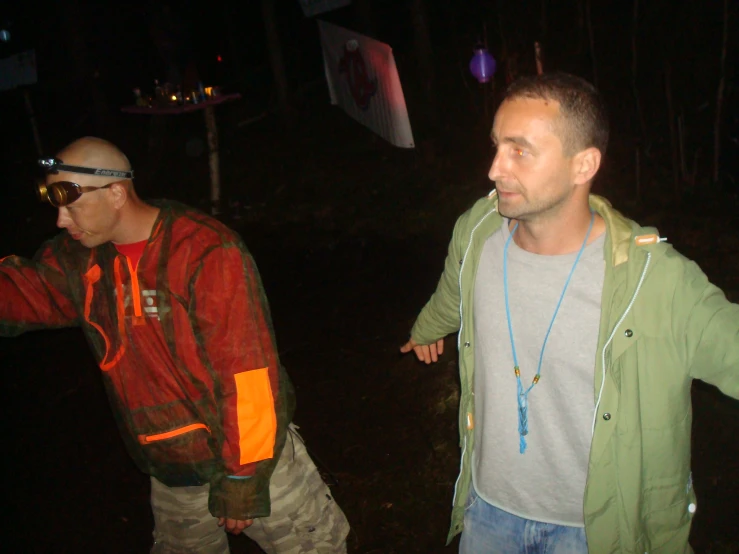 two men standing next to each other in the dark