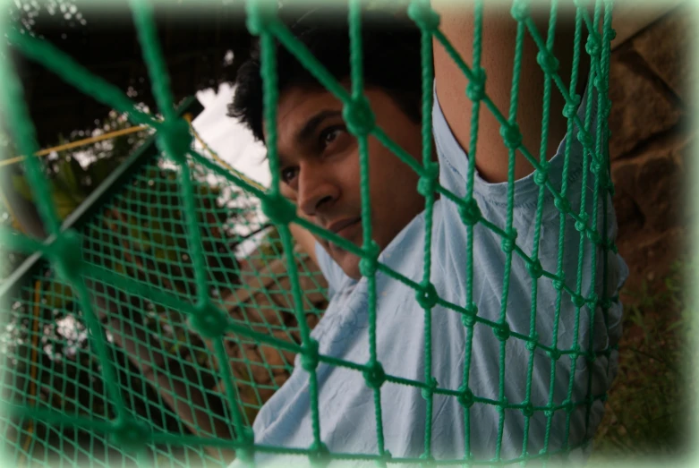 a man is posing behind the green fence