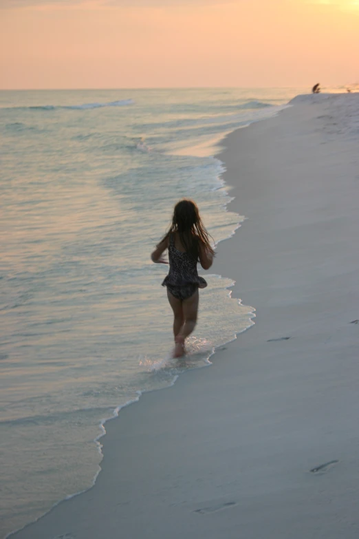 a girl running out to the water at sunset