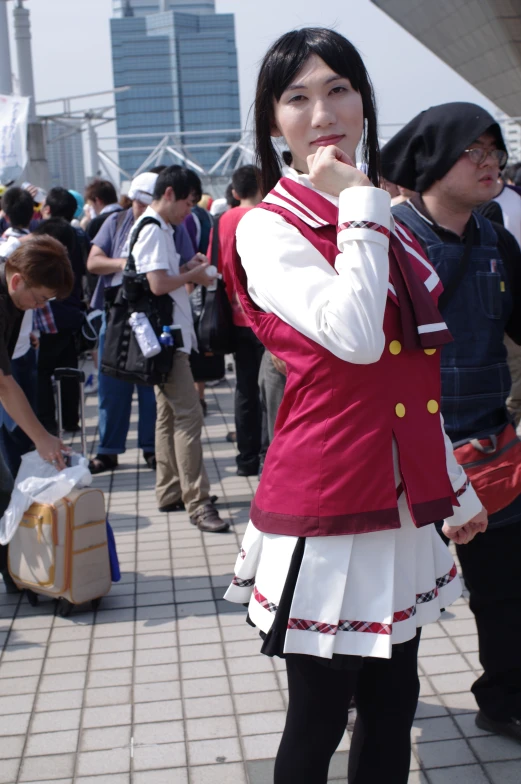 girl with white and maroon uniform, standing on brick sidewalk in public