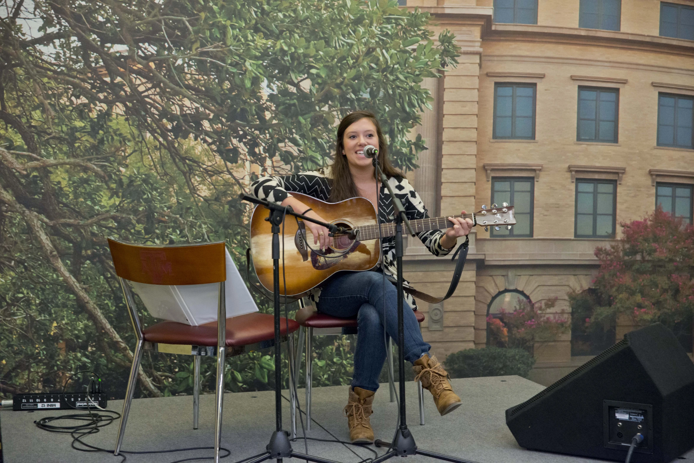 a woman sitting on a bench playing an acoustic guitar