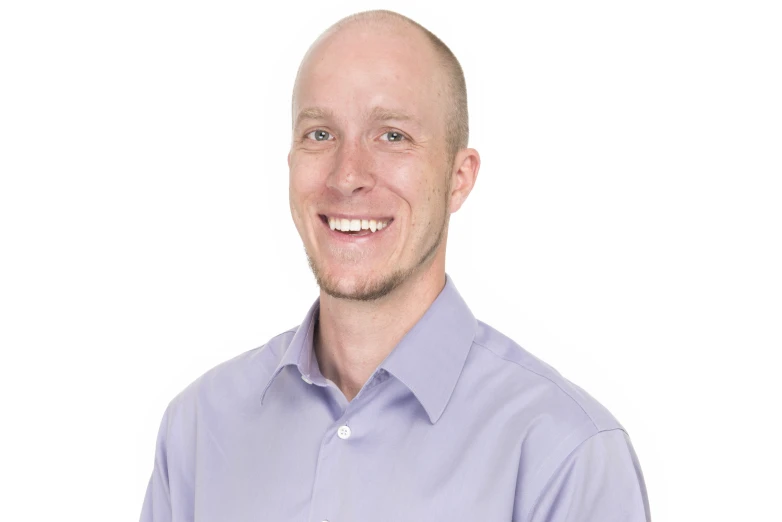 a man wearing a purple shirt smiles in front of a white background