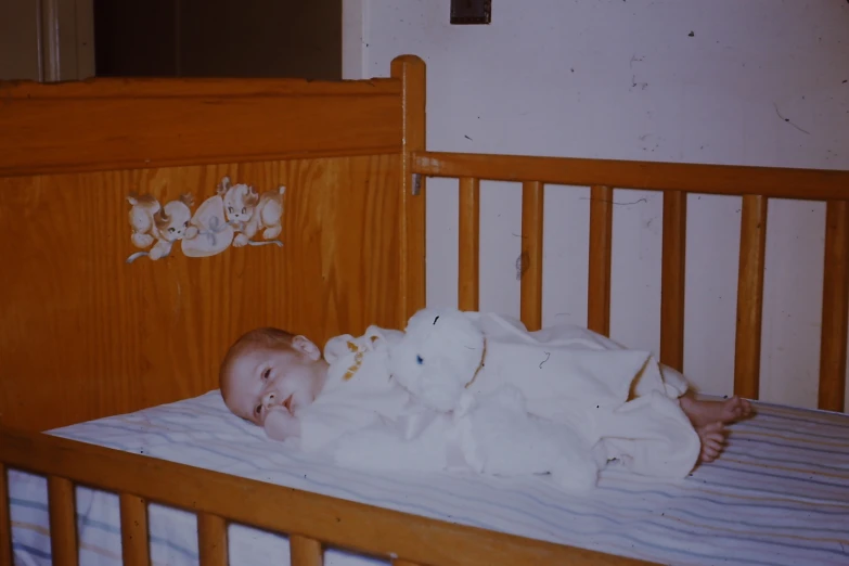 a baby with one leg out in an empty crib