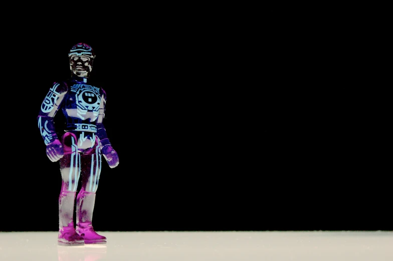 a purple toy figurine standing on a black background