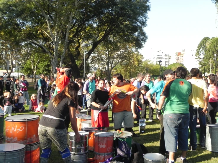 a group of people stand around buckets and drums