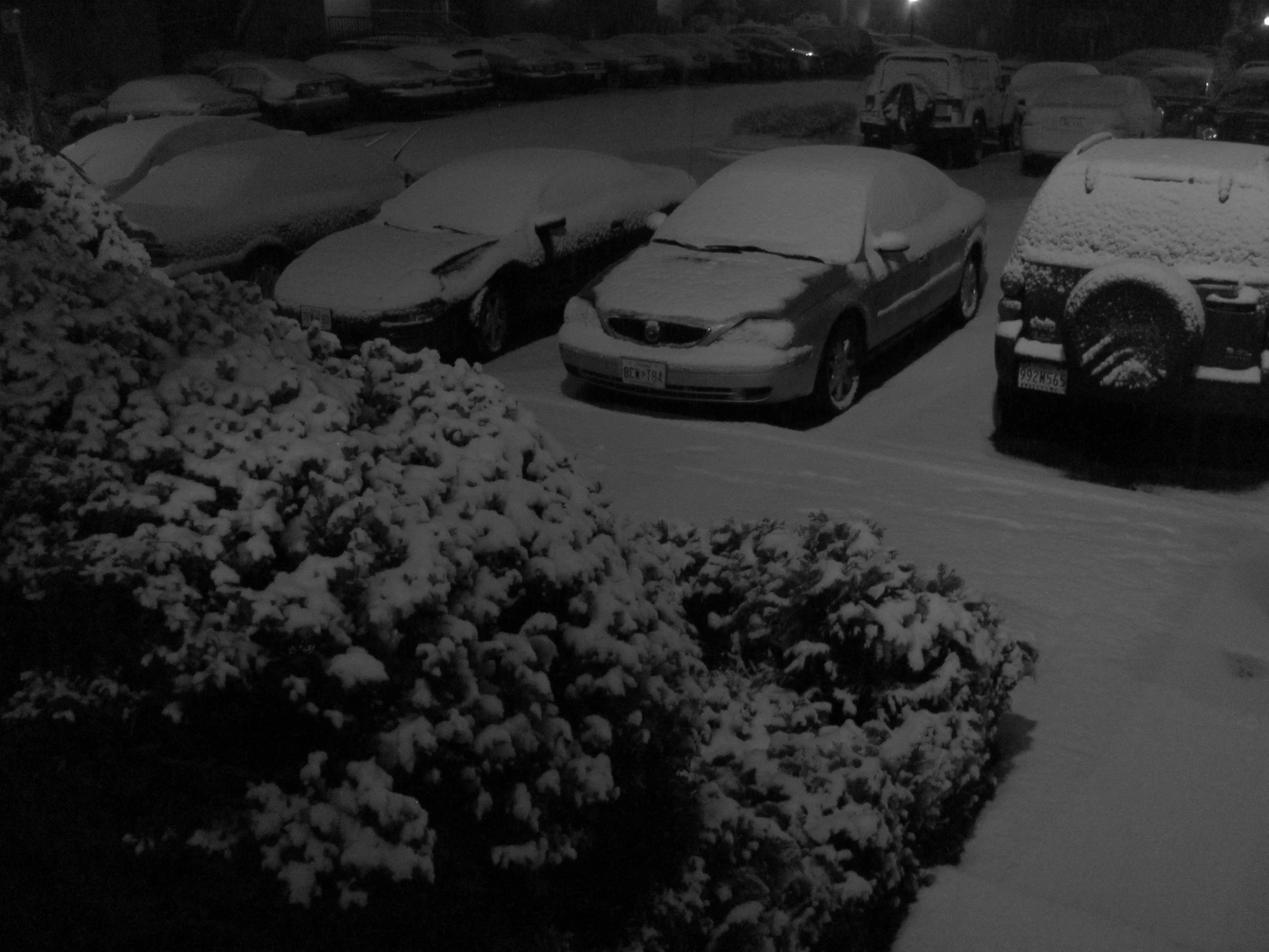 a parking lot with snow piled on it at night