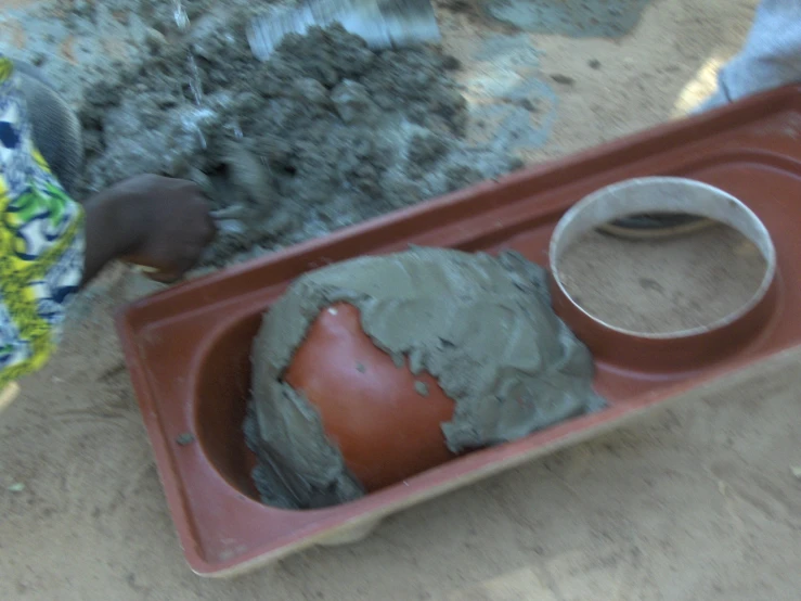 a child holds the bottom half of a plastic tray with plastic clay and a candle