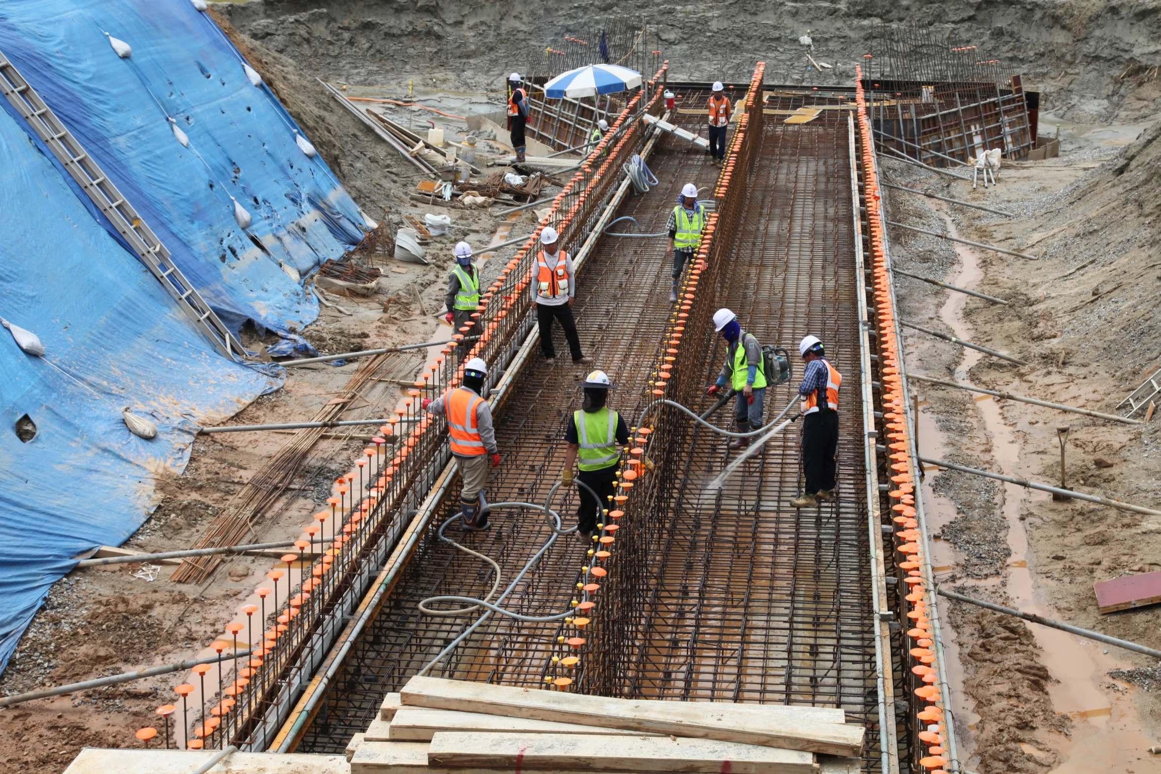 several workers at an industrial construction site pouring concrete