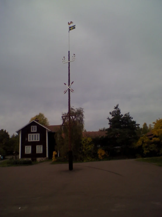 a red house with wind vane and flags next to tree