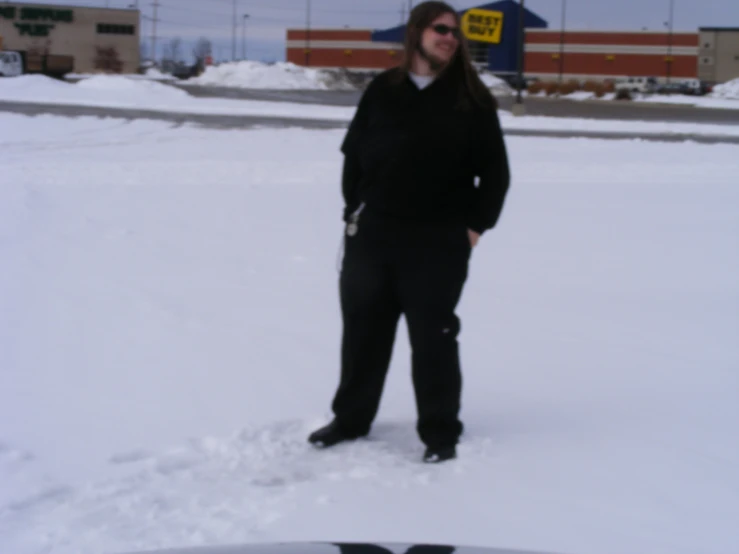 a person standing outside in the snow near a board