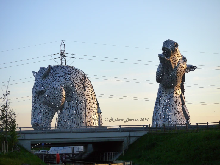 sculptures near the highway with cars passing underneath