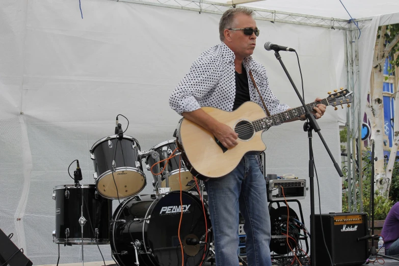 a man playing guitar next to another man singing into a microphone