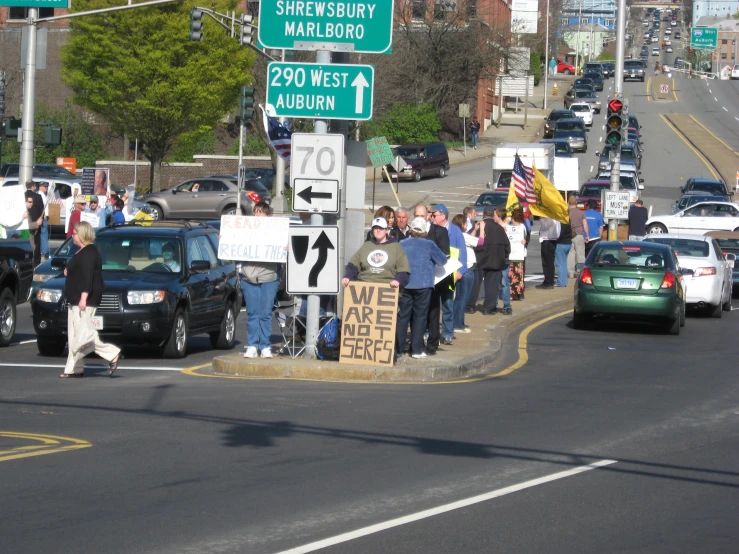 group of people standing on sidewalk next to a street sign