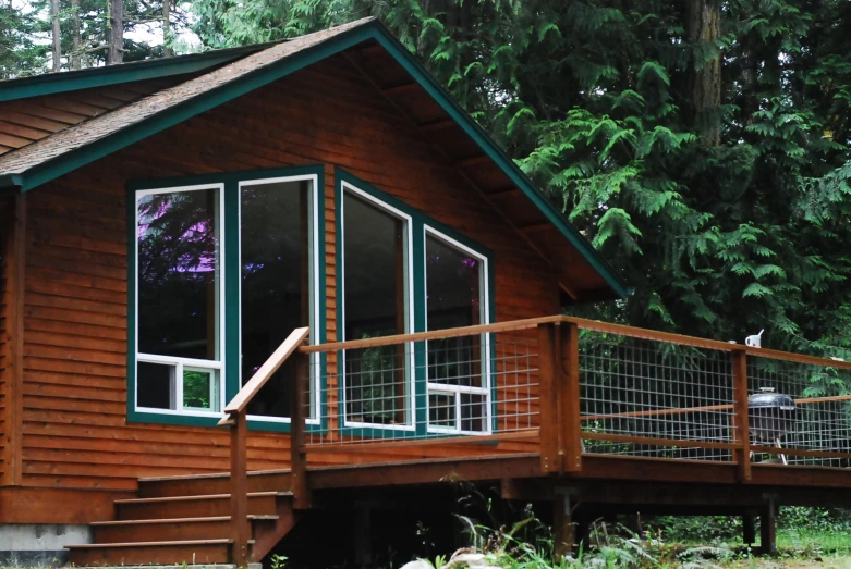 wooden cabin with green door and balcony overlooking trees