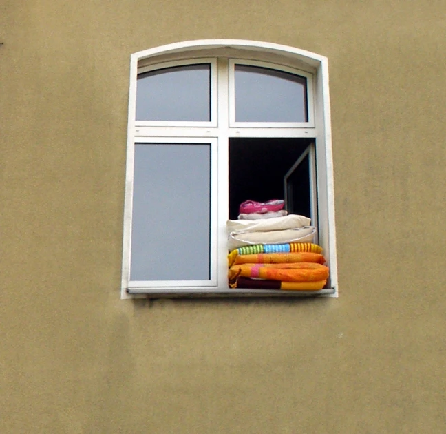 a brown building with an open window and some towels on it
