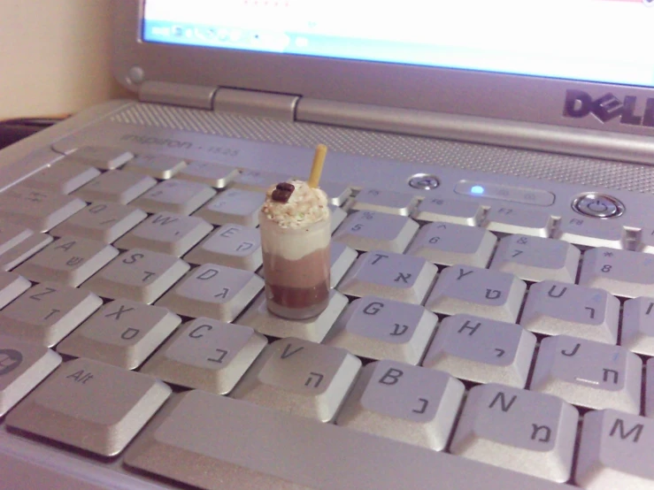 a small drink sitting on top of a laptop keyboard