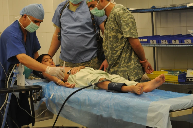 a group of men standing around a person in a hospital