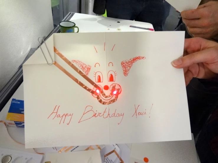 a hand holding a birthday card that has been placed on a table