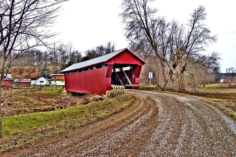 a red covered bridge with some snow on it