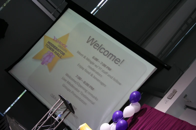 the purple and white balloons are by the welcome sign