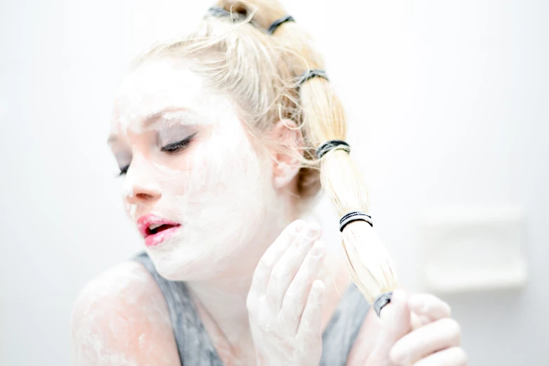 a woman holding a brush to her face while she uses foam on it