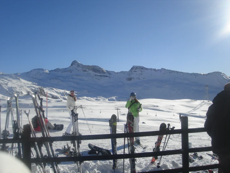 a group of skiers on the snow next to a fence