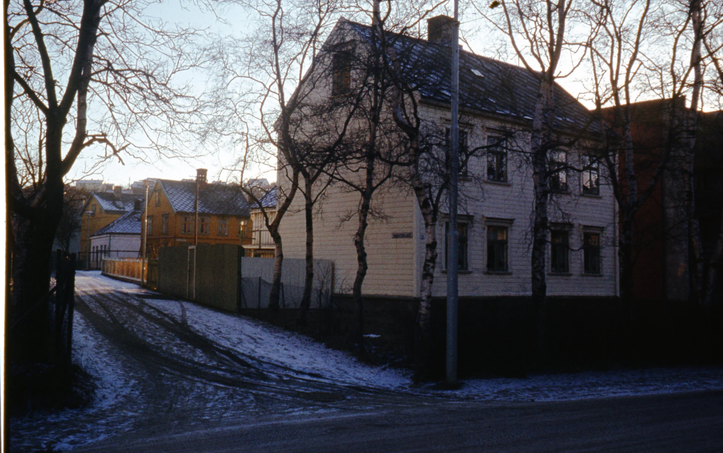 a snowy road is in front of a yellow building